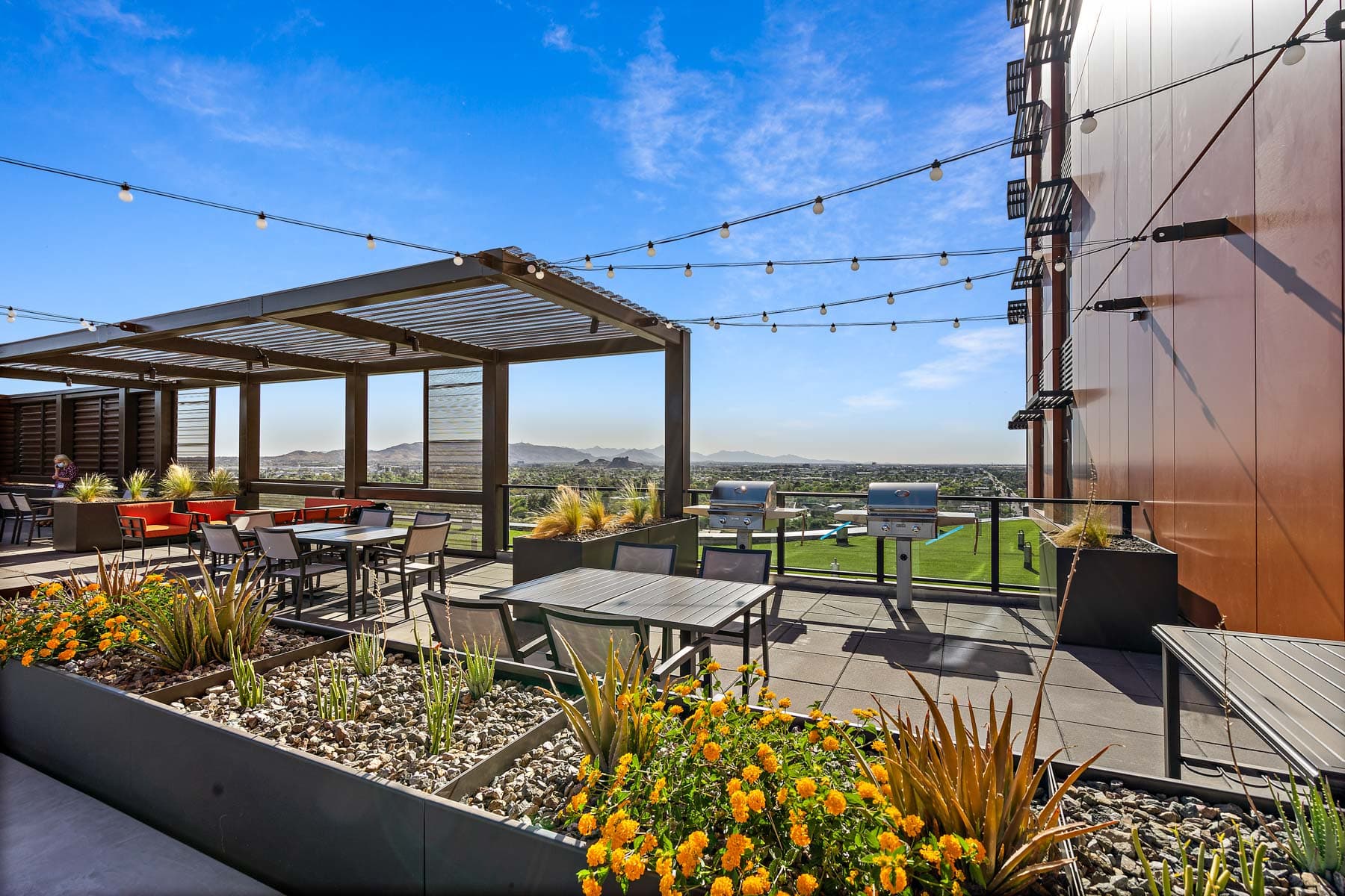 A rooftop patio at Mirabella at ASU. There are grills, tables and chairs and comfortable couches.