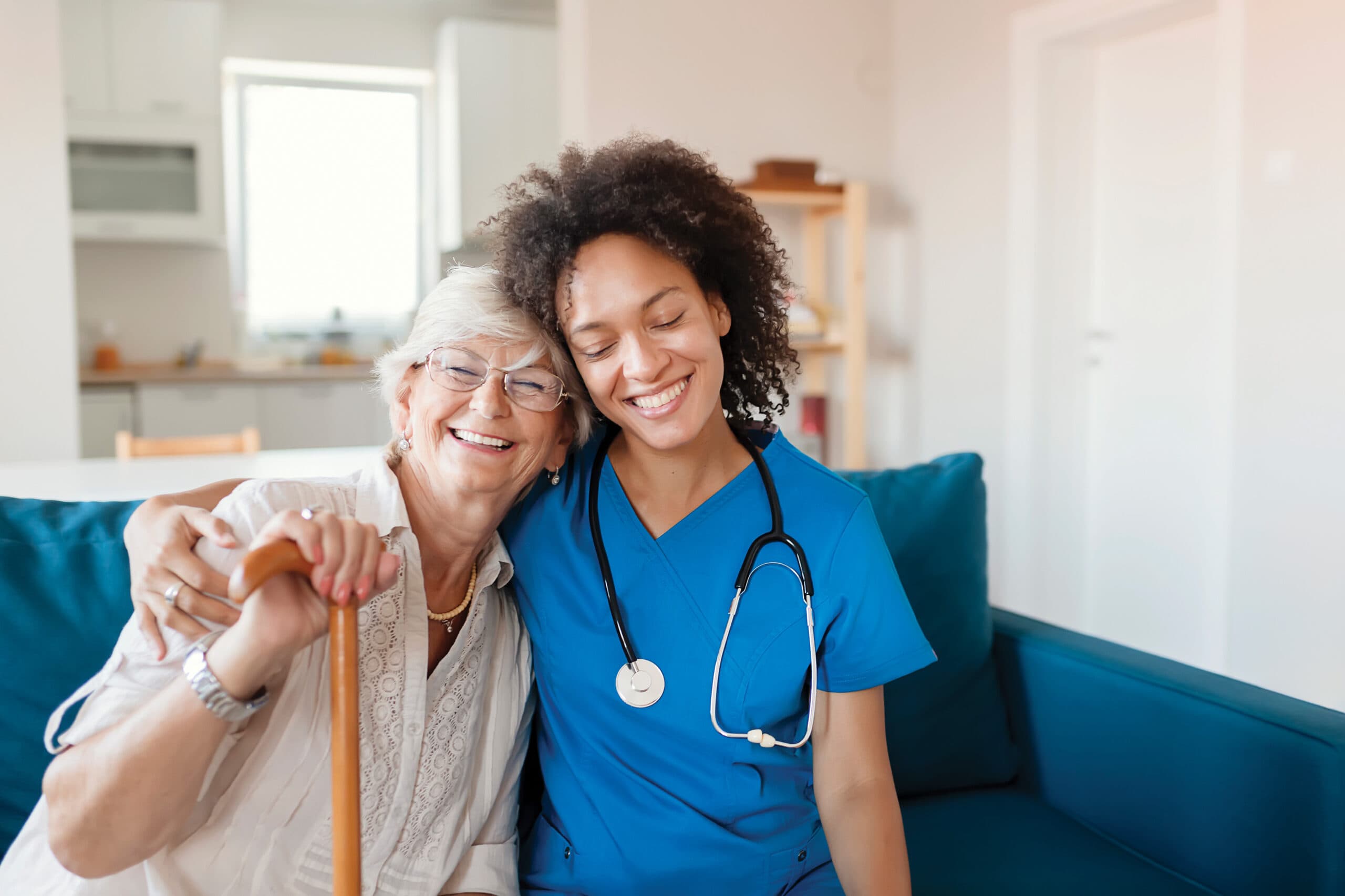 A compassionate nurse hugs an older woman.